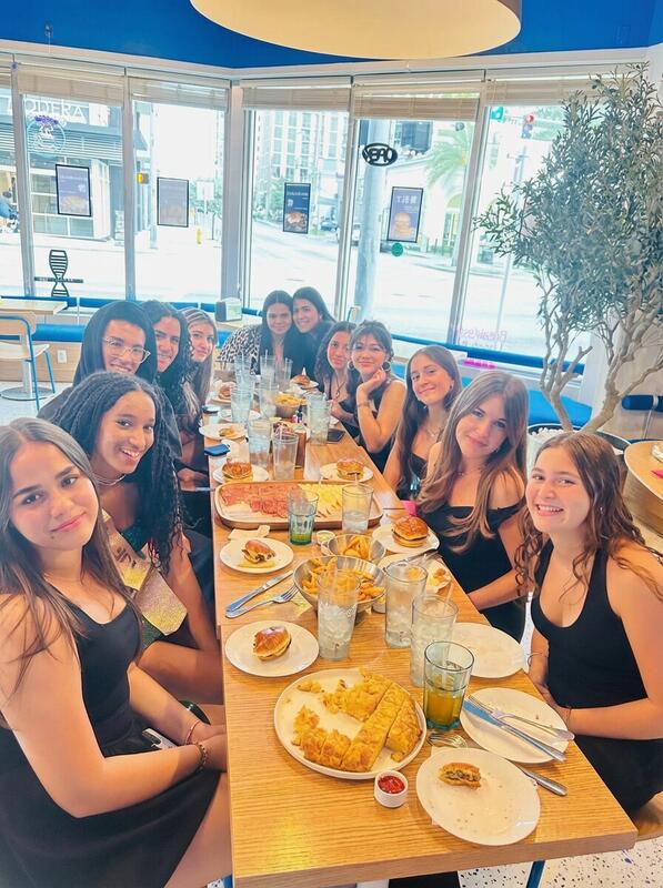 Happy customers dining inside Redondos Miami — large group enjoying smash burgers and platters in modern blue interior