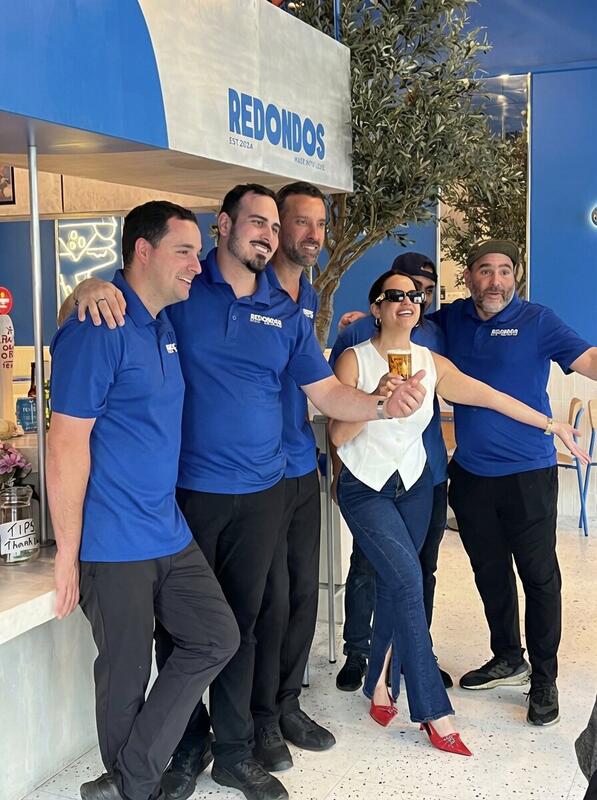 Redondos team in blue uniforms posing together inside the restaurant with owner Carmen — Made With Love sign in background